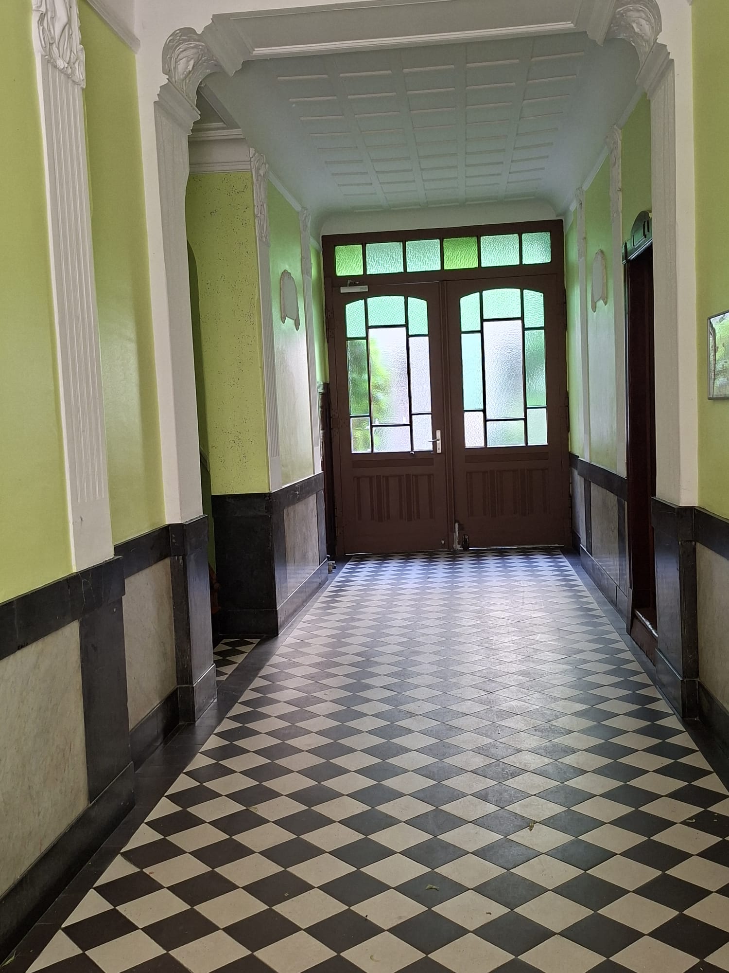 Historischer Hausflur mit grünen Wänden und Schachbrettfliesen