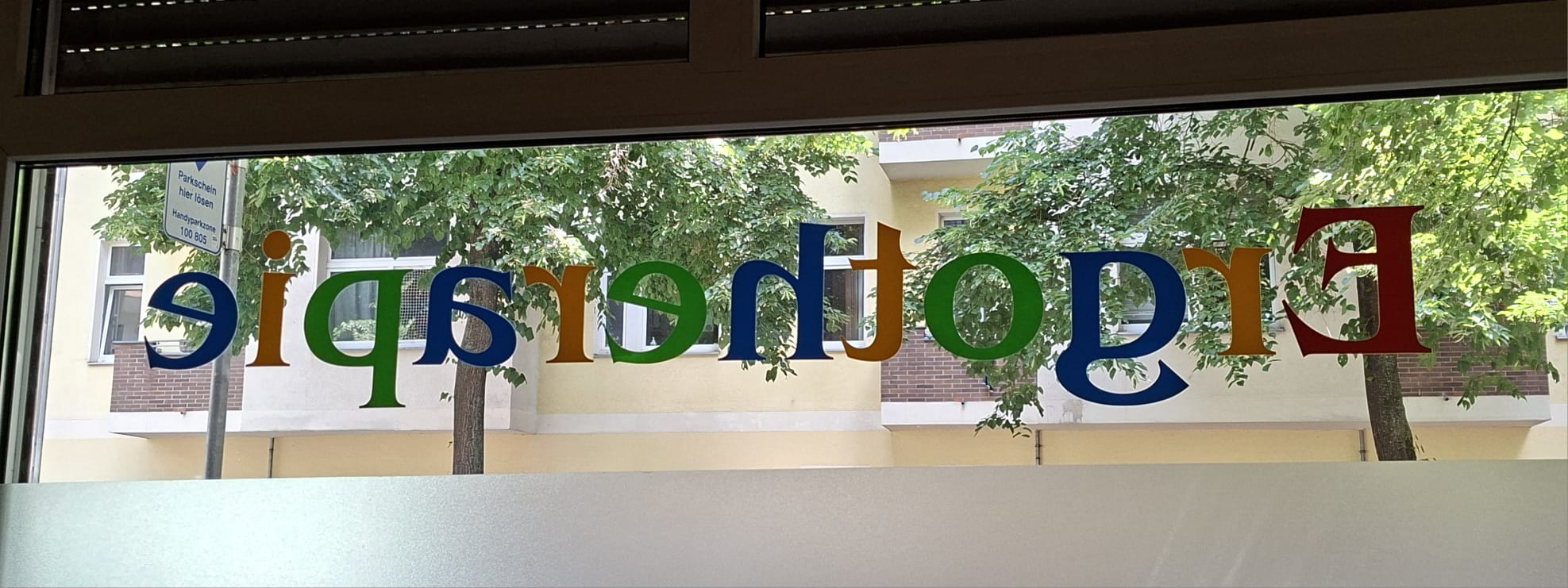 Buntes Praxisschild Ergotherapie am Fenster