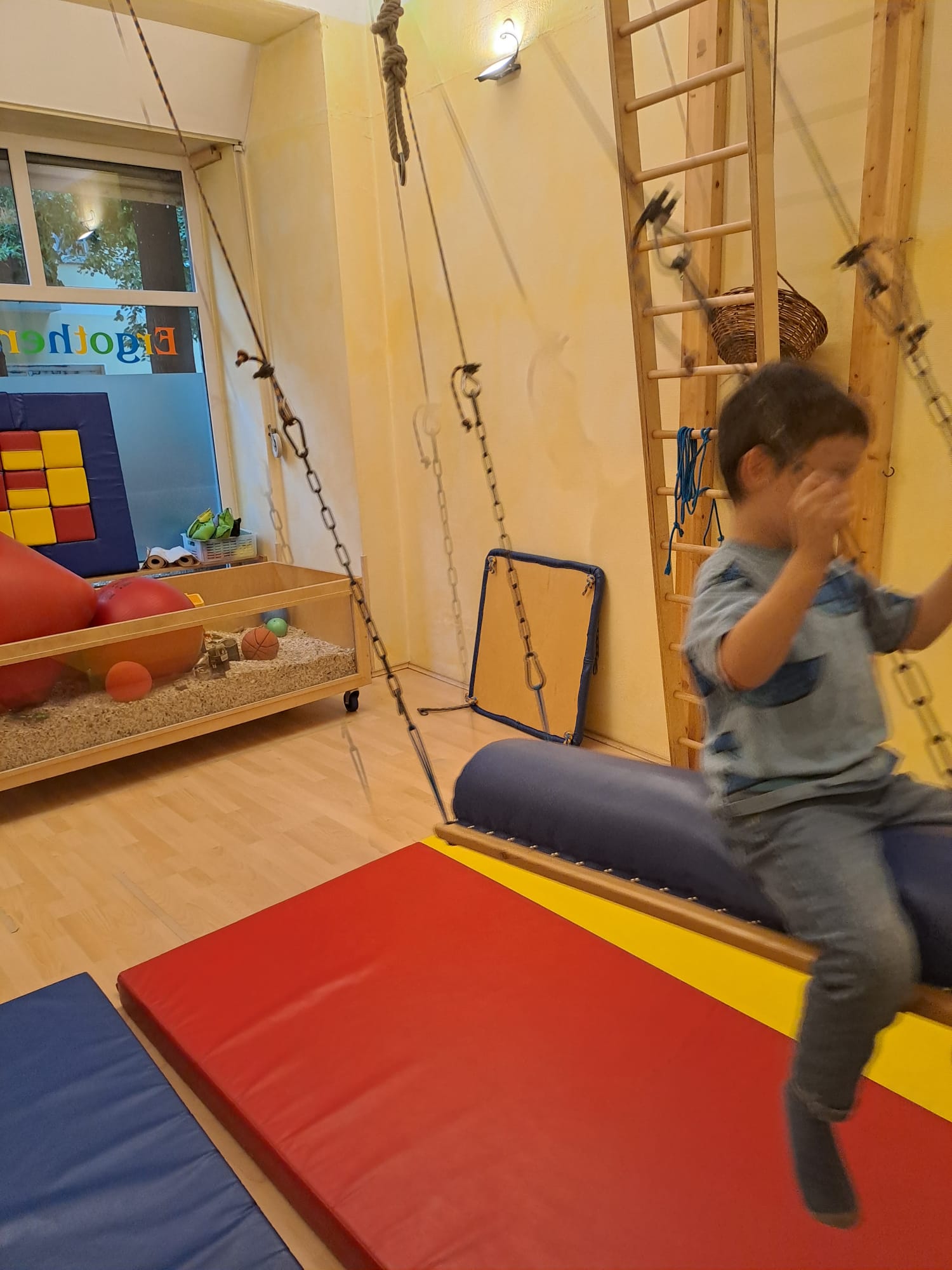 Kind schwingt auf einer Therapieschaukel im Pädiatrieraum