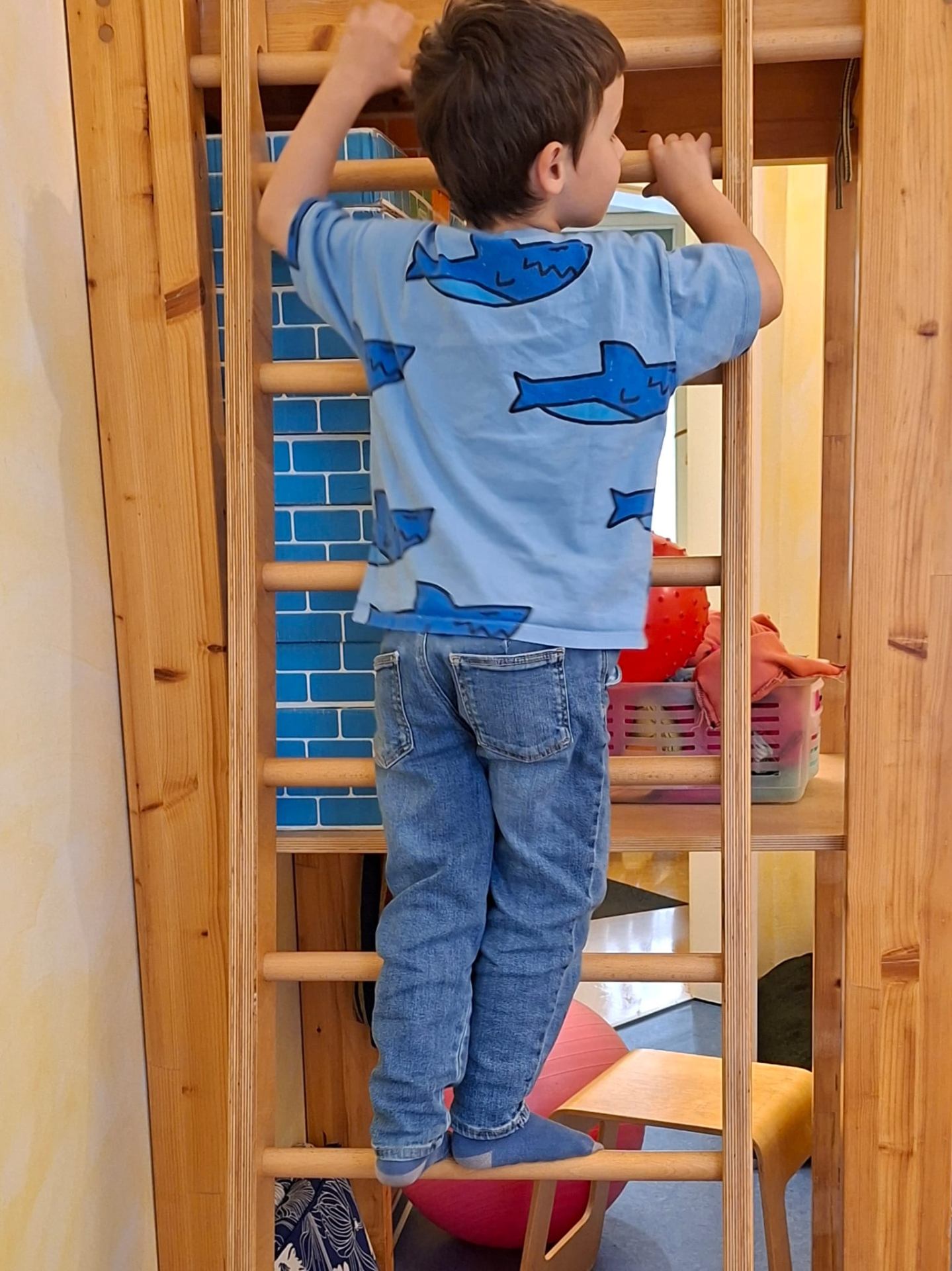 Kind klettert an einer Sprossenwand aus Holz